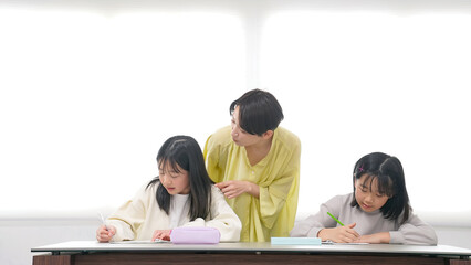 勉強する二人の女の子と女性教員