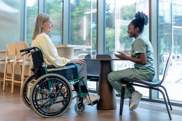Doctor and patient on a wheelchair talking and looking peaceful