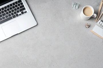 Modern clean business workspace with laptop and coffee on grey surface

