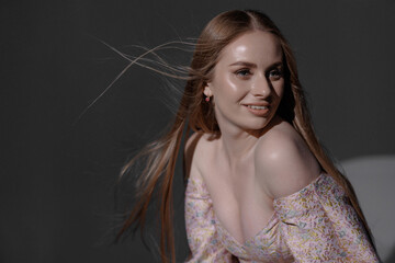 Elegant woman with long hair poses playfully in soft light during a fashion shoot