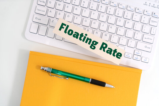 A piece of paper with green text reading 'Floating Rate' placed above a white keyboard, alongside a yellow notebook and green pen , representing the concept of floating rate financial instruments