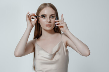 Woman applying mascara in a stylish setting with soft lighting showcasing beauty