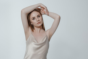 Young woman poses gracefully against a neutral background in minimalist fashion attire during a studio shoot