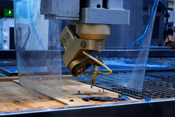 Close-up of industrial waterjet cutting machine nozzle during operation.