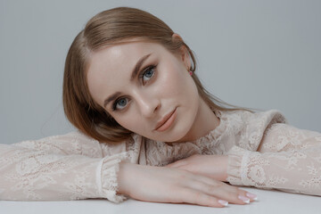 Young woman poses gracefully with a soft expression, showcasing elegant fashion in a minimalist setting