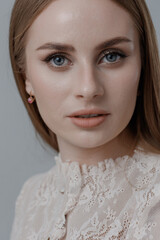 Captivating portrait of a woman with lace attire and subtle makeup highlighting her natural beauty in a neutral setting
