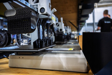 3D printer in action, fabricating parts on a build plate in a modern manufacturing facility. Focus on innovation and industrial technology.