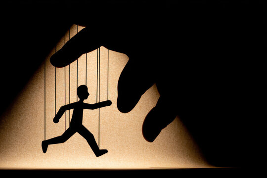 Silhouetted puppet manipulated with strings against a dramatic light background