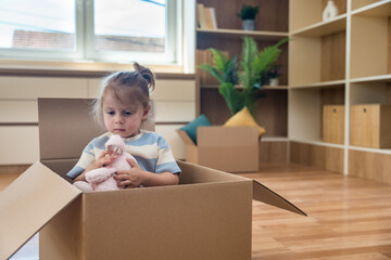 Baby girl in the cardboard box. Young happy child with imagination inventing a game to play at home...
