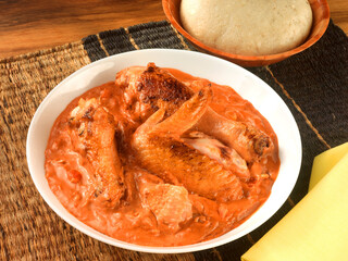 ChickenPeanutSa-Angola, Haehnchen in Erdnussauce auf Rattanset mit gelber Serviette