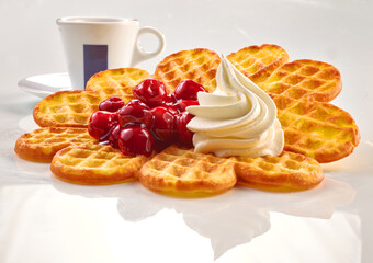 Waffel mit Kirschen und Sahnetupfer mit Espressotasse auf weissem Fond, Gebäck