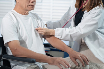 Obraz premium Doctor with stethoscope examining elderly patient sitting in a wheelchair with examination, recommending treatment, healthcare and medical concept.