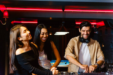Two diverse young women dancing happily next to a smiling DJ at a neon-lit nightclub. Captures vibrant nightlife, party joy, and entertainment with a modern, inclusive social scene vibe.