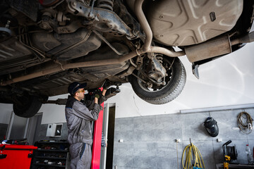 Mechanic inspecting the underside of a vehicle in a professional garage environment
