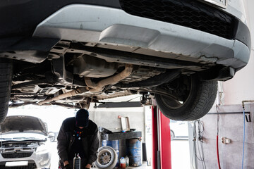 Mechanic inspecting vehicle underside on lift in automobile repair shop