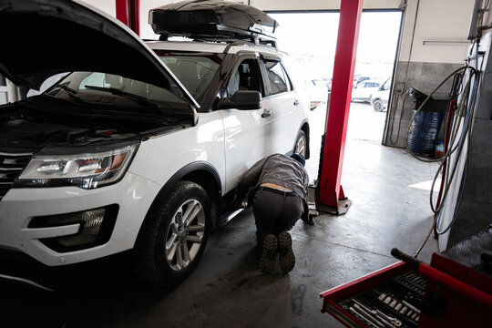 Mechanic inspecting vehicle undercarriage in a professional auto repair workshop