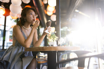 Young woman enjoying ice cream in a modern cafe with warm lighting and cozy atmosphere