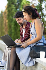 Young professionals engaged in outdoor collaboration with a laptop, discussing creative ideas during a sunny day in a park setting