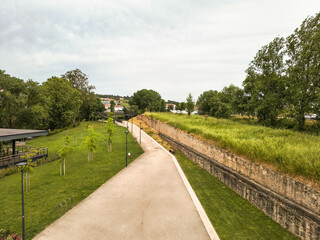Serene park walkway with lush greenery  historic stone walls. Evokes tranquility and reflection. Ideal for travel, landscaping,  urban design themes.