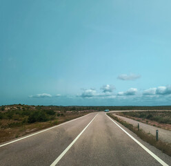 Open road under a bright sky. The asphalt highway stretches to the horizon, a symbol of freedom,...