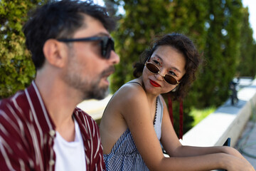 Young woman in sunglasses enjoying conversation with friend outdoors on a sunny day