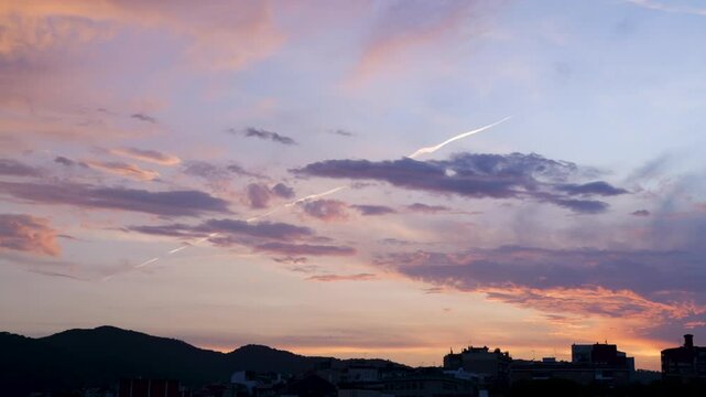 A horizontal panning shot of a vibrant sunset over the city of Matar&oacute;, Spain. Colorful clouds, mountain silhouettes, and urban rooftops create a peaceful scenic view.