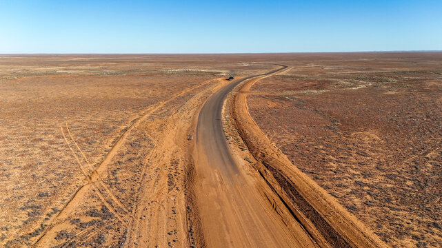 Aerial of dirt road meeting the tar in the outback - sealed to unsealed road