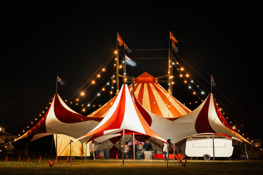 Motion blur people outside big top circus tent at night