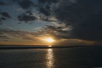 Sunset over calm waters with clouds reflecting favorite hues in a coastal view