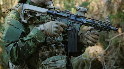 Fototapeta premium Soldier holding automatic rifle during military training in forest