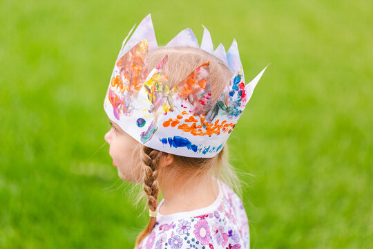 Young girl outdoors wearing handmade painted paper party crown
