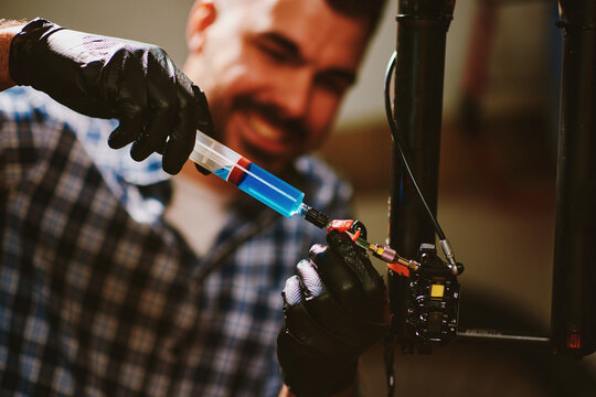 Bicycle mechanic injecting lubricant into hydraulic brakes in workshop