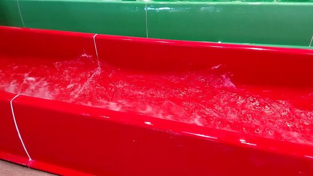Splashing water in the chute of a brightly colored waterslide, a place to relax and have fun on the water