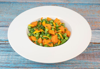 Fresh garden peas and carrots are cooked with salted butter, then garnished with chives and bright...
