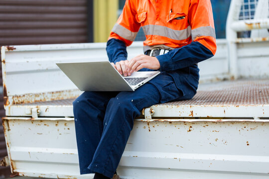 teenaged trainee tradie apprentice working on laptop in back of ute in high-vis workwear