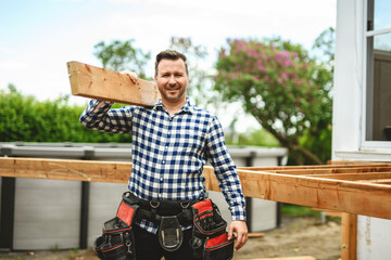 Handyman worker making patio outside close to a pool holding wood