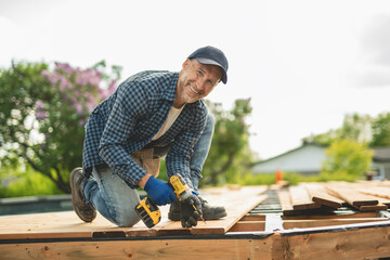 Handyman worker making patio outside close to a pool installing floor.