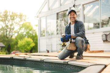 Obraz premium Handyman worker making patio outside close to a pool installing floor.