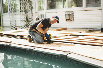 Handyman worker making patio outside close to a pool installing floor.