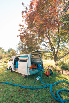 Small white van with commercial carpet steam cleaning equipment parked outside home with hoses