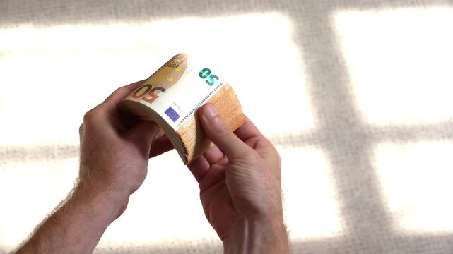 Une grosse liasse de billets de 50 euros tenue en mains