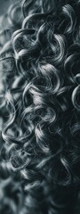 A close-up view of vibrant, textured curly hair, showcasing intricate spiral patterns and rich detail in monochrome tones.