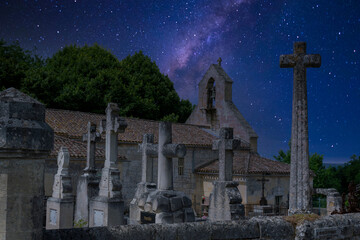 In Saint-Laurent-des-Combes, stone crosses stand solemnly in a quiet cemetery, framed by a stunning night sky filled with stars. The church adds to the serene atmosphere.