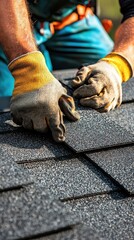 Close-up of hands wearing gloves installing dark asphalt shingles on a roof under natural sunlight with detailed texture