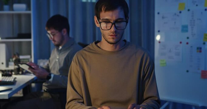 Team adult male freelance developer work late typing write prompt AI bot app program nomad terminal code at office night. Artificial intelligence dashboard, robotics, user interface, machine learning.