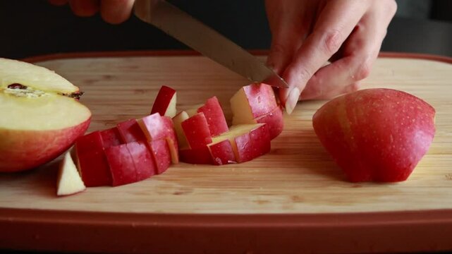 woman&rsquo;s hands slicing a fresh apple at home on a wooden cutting board
