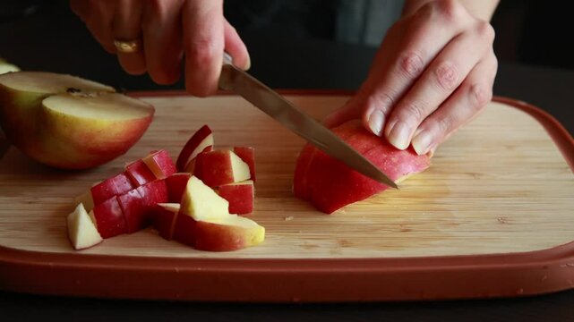 woman&rsquo;s hands slicing a fresh apple at home on a wooden cutting board