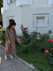 A young girl stands and looks at the roses