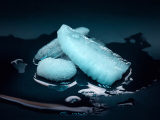 Ice melting. Melting ice chunks on dark background. Blue backlight
