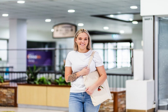 portrait of young Australian woman in her twenties out shopping at mall carrying tote bag
